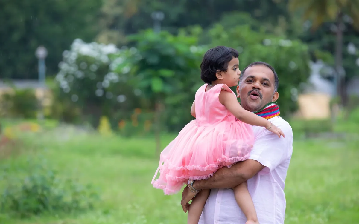 An Indian father carrying his little daughter in a garden