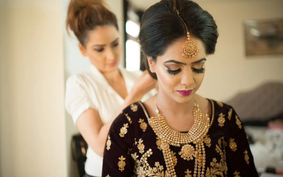 A bride having her jewellery adjusted while getting ready
