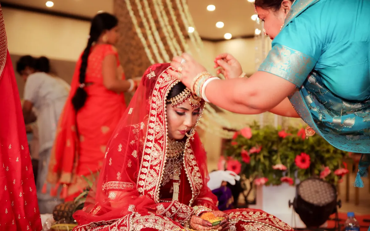 An older woman helping a bride with her bridal jewellery
