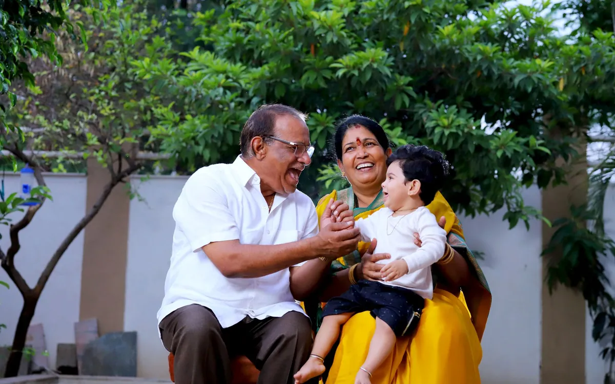Indian grandparents laughing with their grandchild in a garden