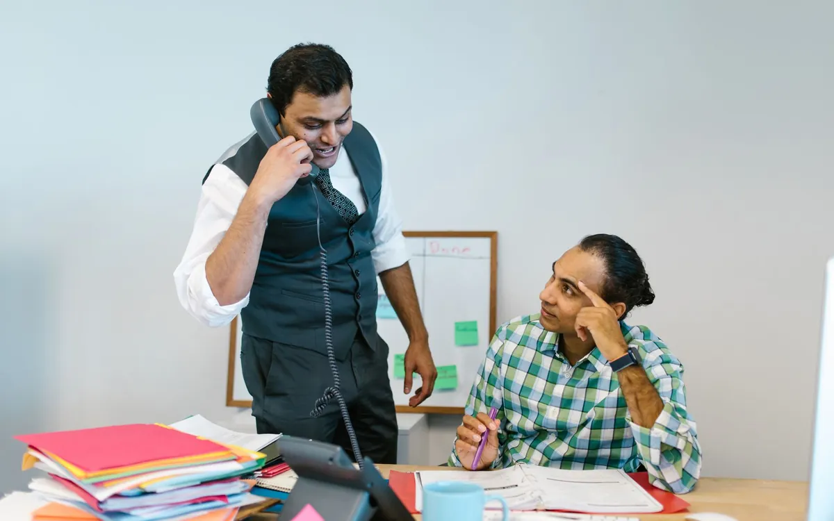 Two Indian men at work in an office, one on the phone