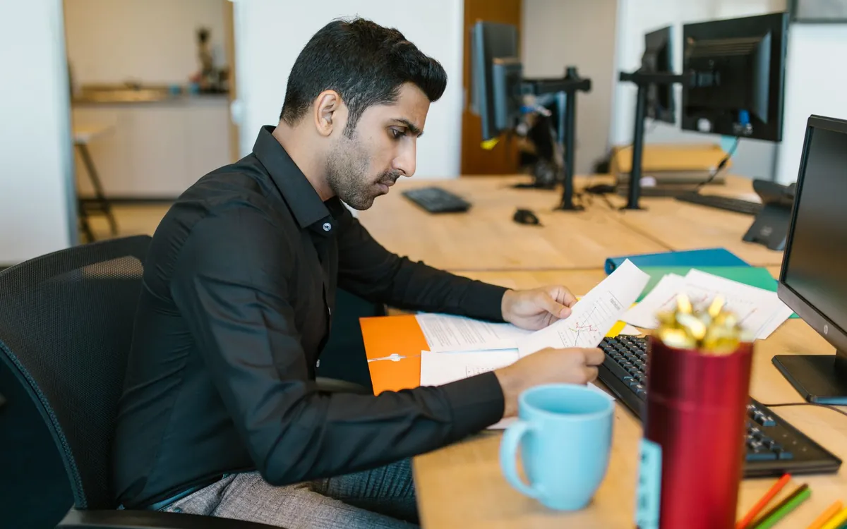 An Indian man reviewing papers at his office desk
