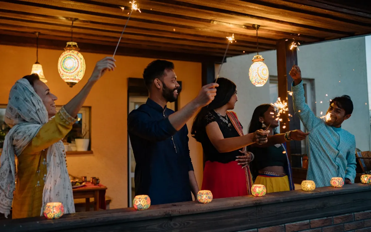 A family lighting sparklers on a balcony during Diwali