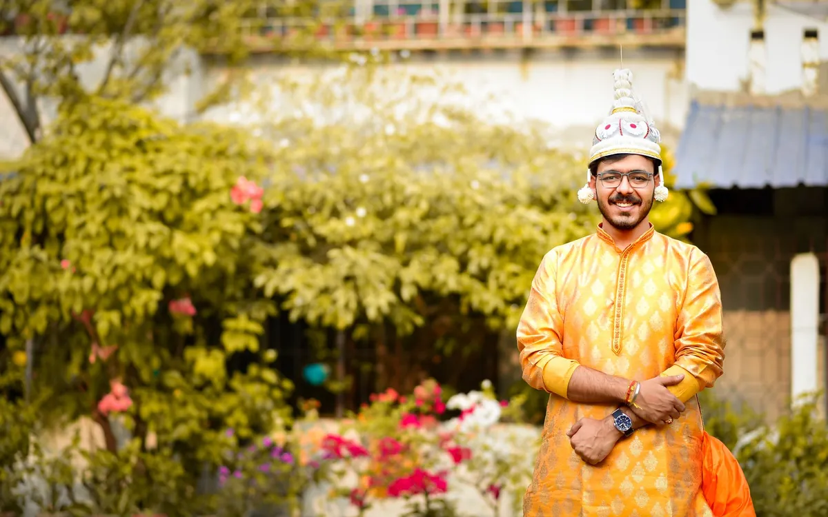A young Indian man in a yellow kurta standing in a garden