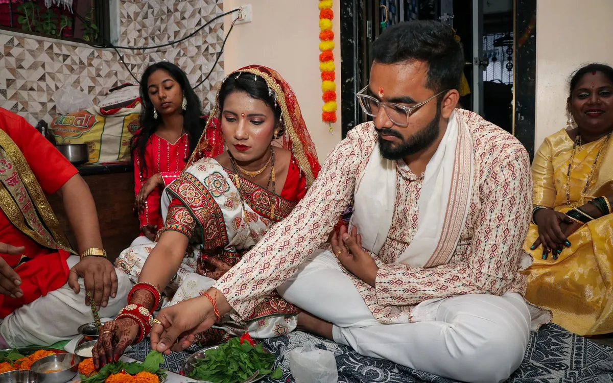 A newly married couple performing a ritual with family around them