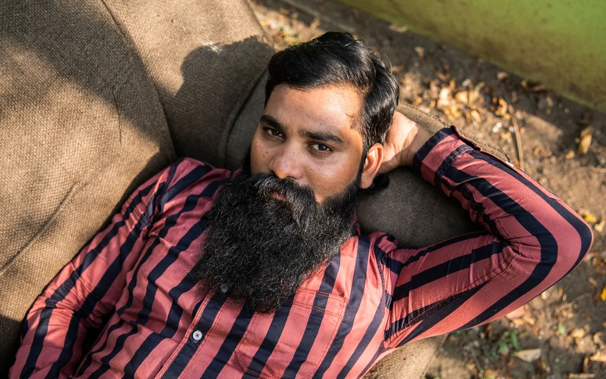 A bearded Indian man lying back, lost in thought