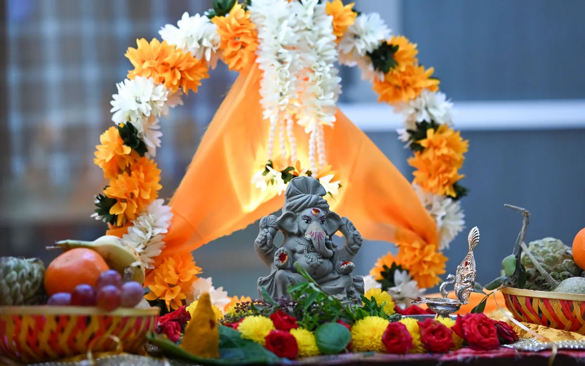 A Ganesha idol decorated with marigold garlands and fruits