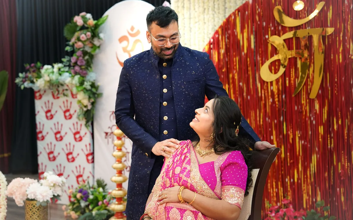 A couple posing at an engagement function with decorations behind them