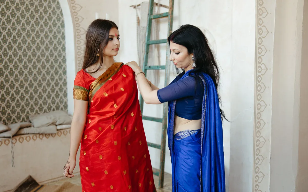 An Indian mother adjusting her daughter's red saree at home