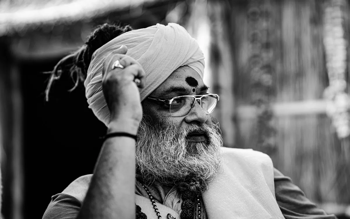 An elderly Indian man in a turban looking thoughtful, in black and white