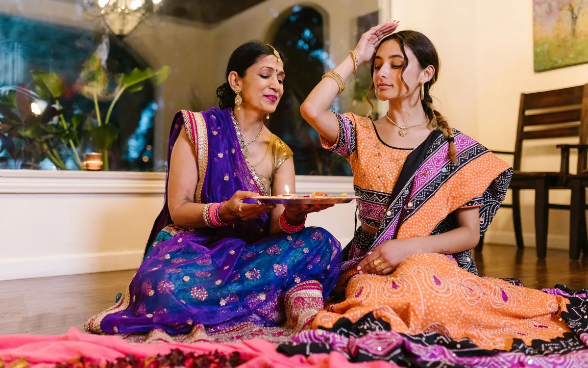 An Indian mother and daughter in sarees discussing matrimony profiles together at home