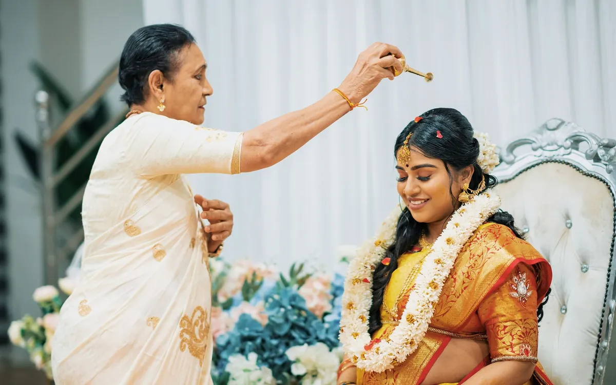 An elderly woman blessing a bride with turmeric