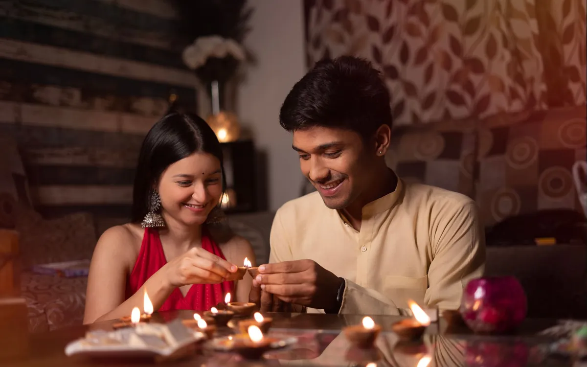 An Indian couple lighting diyas together at home
