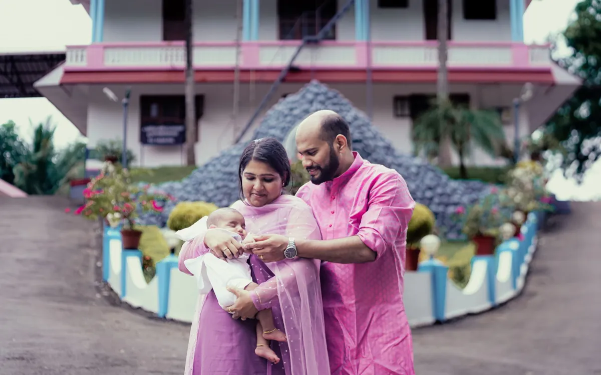 Indian parents holding their baby outside a house