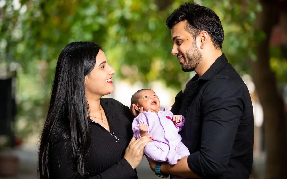 A young Indian couple holding their newborn baby