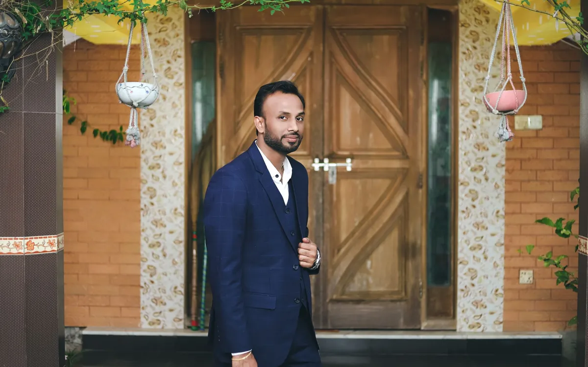 A young Indian man in a suit standing at a front door