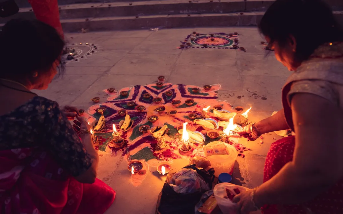 Women lighting diyas around a rangoli during a festival