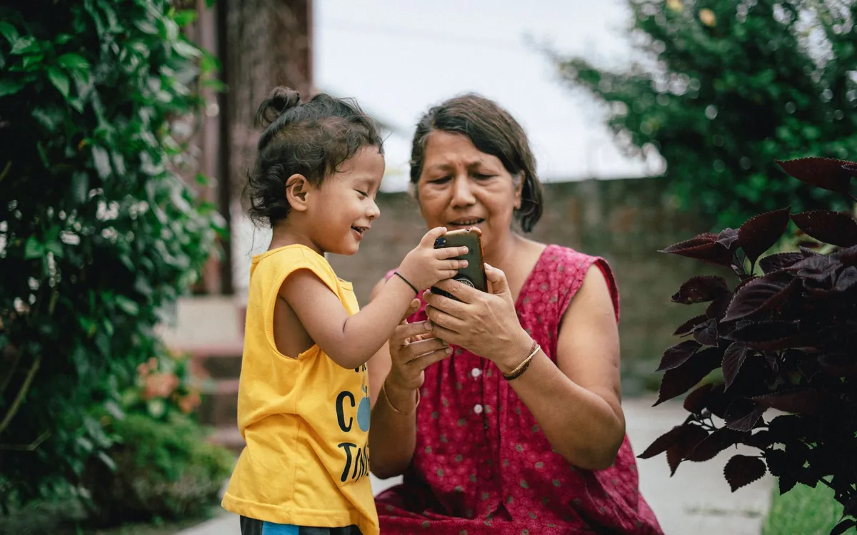 A grandmother and child looking at a mobile phone together