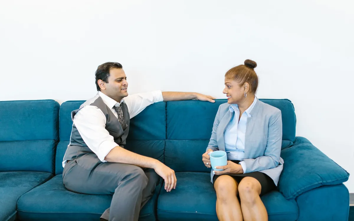 An Indian couple talking on a blue sofa