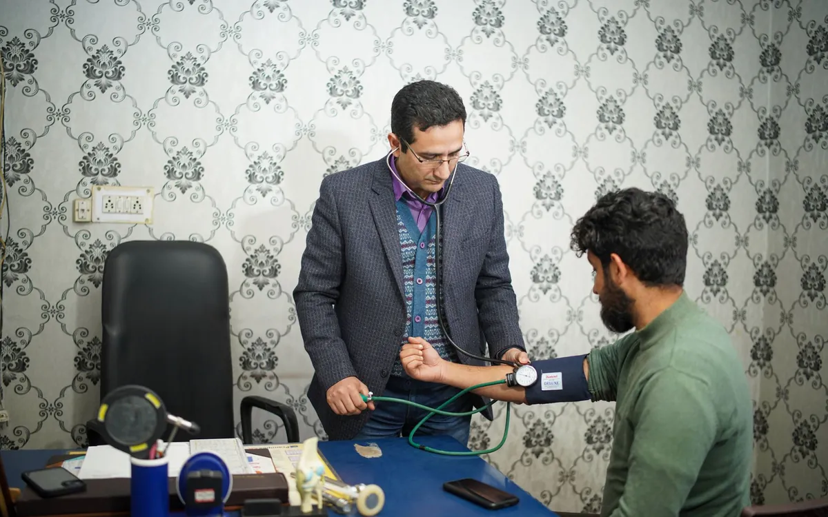 A doctor checking a young man's blood pressure in a clinic