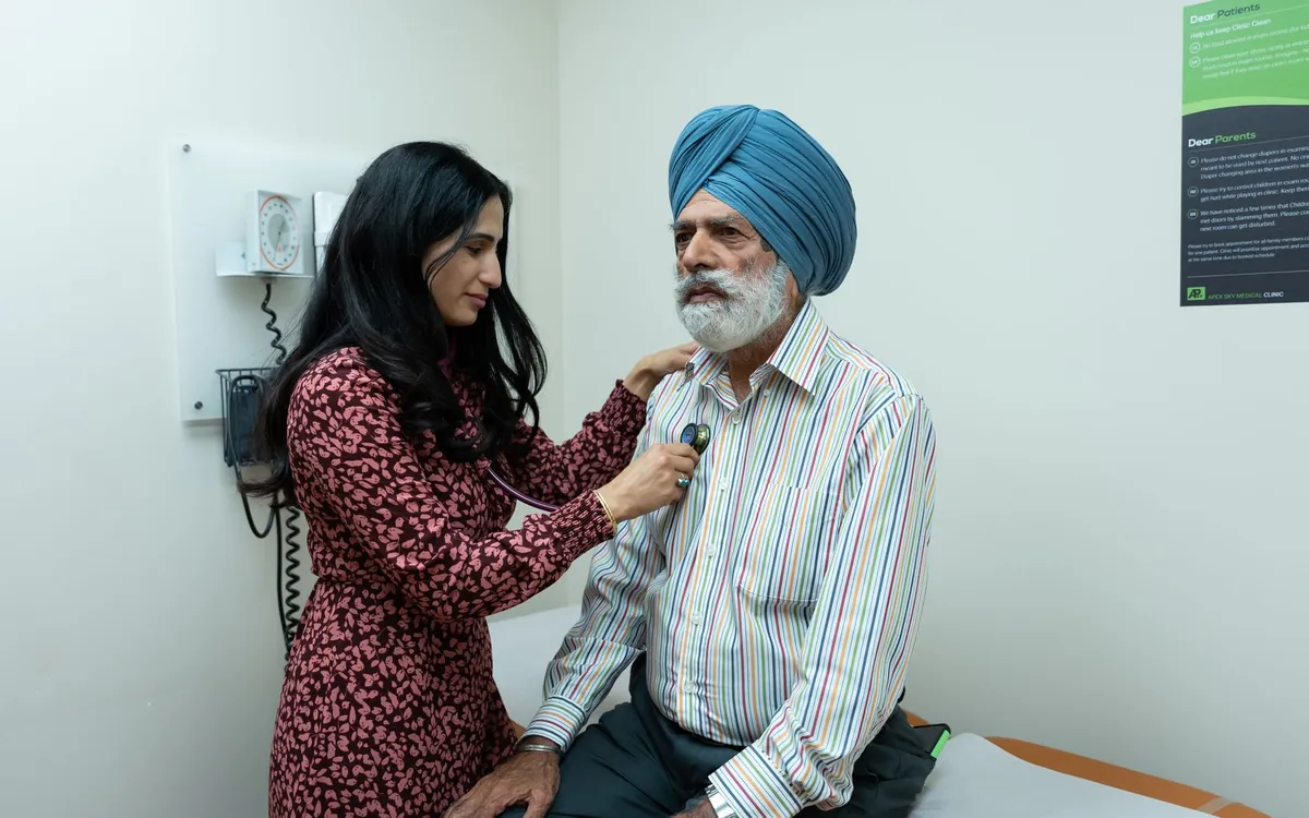 A woman doctor examining an elderly Sikh man with a stethoscope