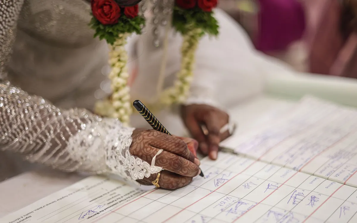 A bride's hennaed hand signing a register