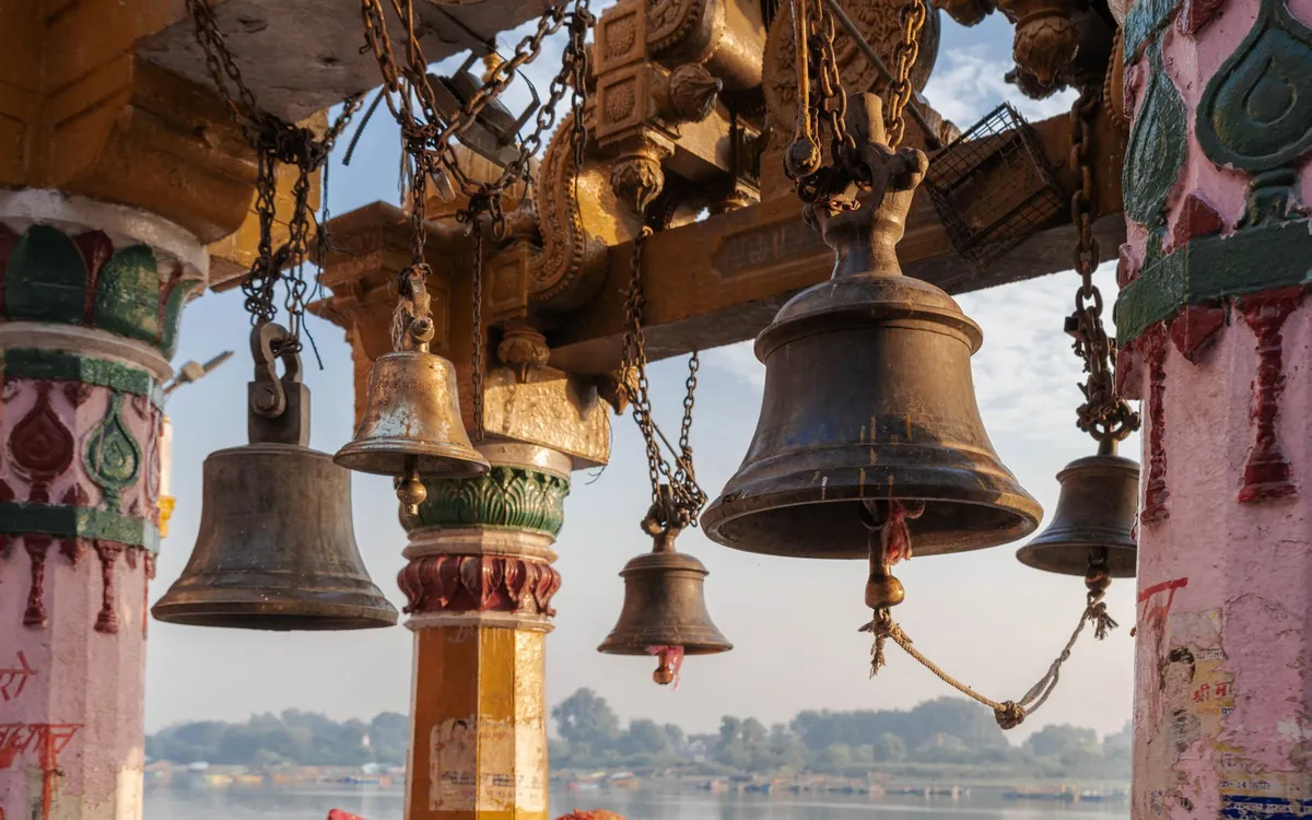 Brass bells hanging at a temple by a river