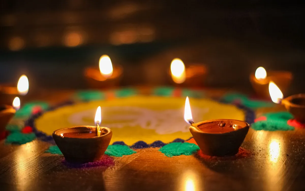 Clay diya lamps glowing on a colourful rangoli during a Hindu festival