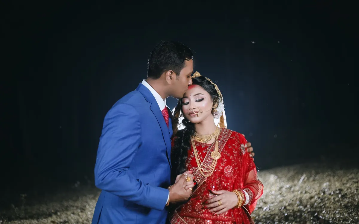 An Indian bride and groom posing together in traditional wedding clothes