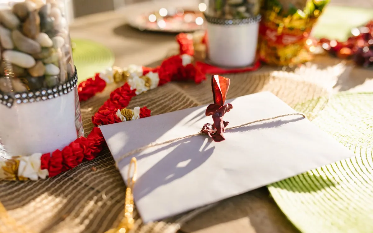 A shagun envelope beside a garland and gifts on a tray