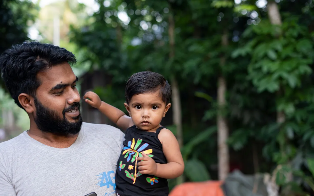 An Indian father holding his young son in a garden