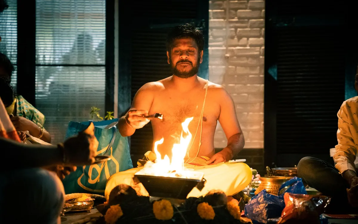 A Hindu priest performing a puja ritual beside a sacred fire